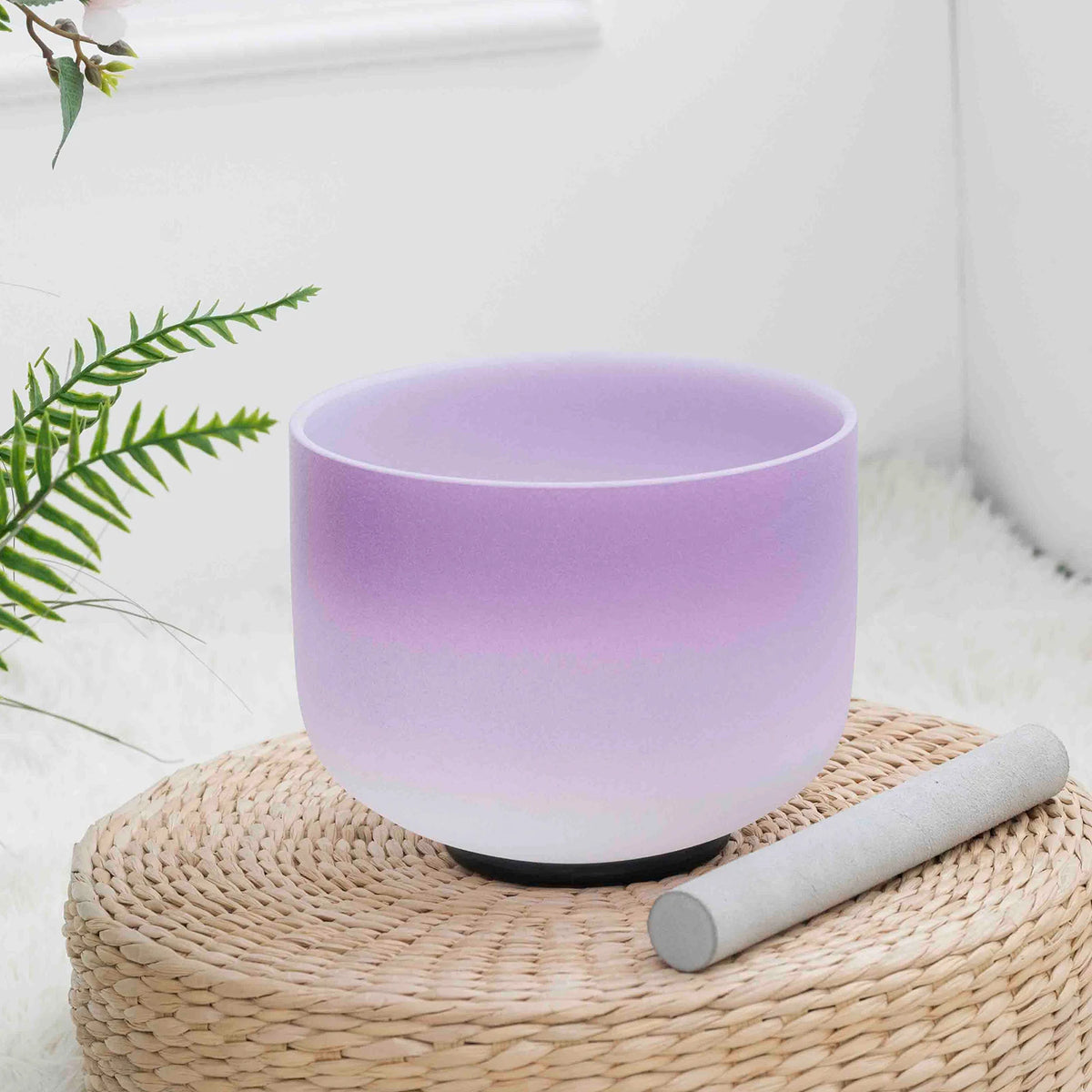 Cuenco morado con degradado claro y baqueta colocada delante sobre un soporte trenzado.