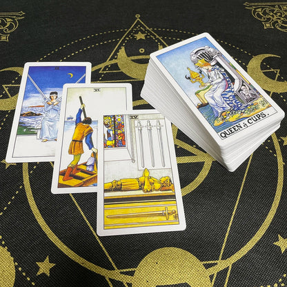 Cartas Rider-Waite con títulos visibles en inglés sobre un mantel negro y dorado.