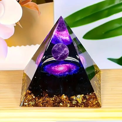 Pirámide decorativa con esfera violeta, motivo de galaxia y base con detalles oscuros y dorados.