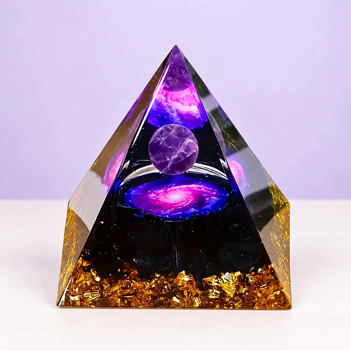 Pirámide Nebulosa con esfera violeta, motivo de galaxia y base con destellos dorados sobre fondo lavanda.